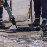 Workers jackhammering broken concrete pavement